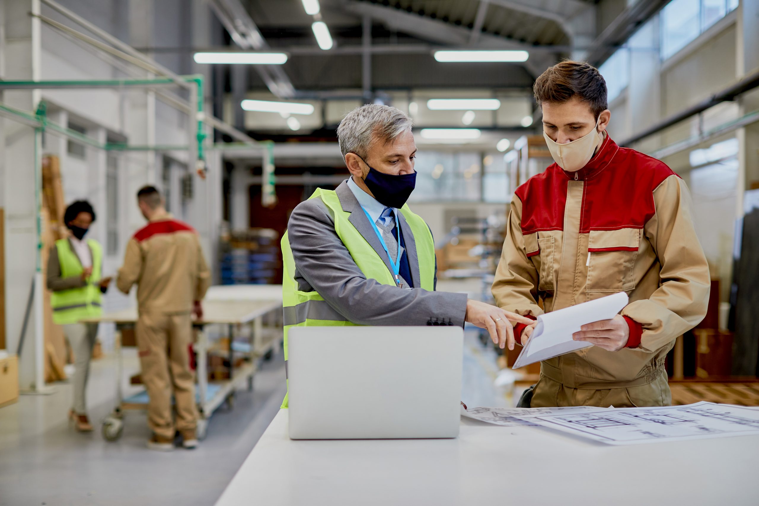 Mid adult engineer and male worker wearing face masks while exam